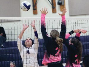 Lady Trojan Alivia Brown attacks the net against a pair of Colonial Beach blockers.