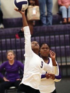 Lady Trojan Leah Coleman delivers a spike as teammate Tai’Leah Cowles looks on.